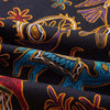 Close-up of dark fabric with colorful bohemian print featuring stylized animals and floral patterns.