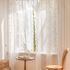 A sheer white floral lace curtain hangs in a large arched window, letting natural light illuminate the room.