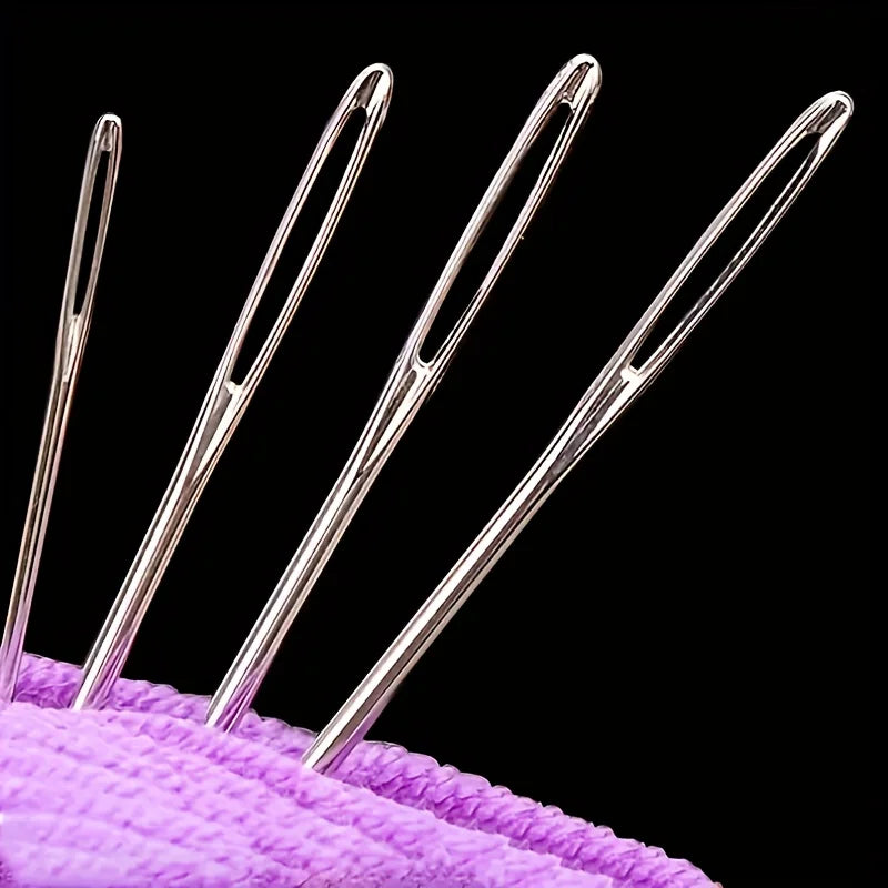 Five stainless steel hand sewing needles arranged diagonally on a purple cloth background.