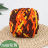A ball of orange, yellow, and brown chenille knitting yarn resting on a woven mat.