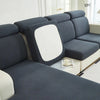 A dark gray jacquard elastic sofa cushion slipcover with a white accent cushion on a light-colored sofa.