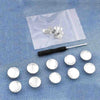 A collection of silver metal button pins is displayed on a translucent plastic sheet against a blue denim background.