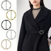 A woman models a black coat featuring a metal round clip buckle detail on the fabric.