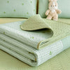 A stack of light green quilted fabric and a beige quilted mat are displayed on a pale green surface.