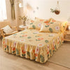 A bed featuring a double layer printed skirt in yellow and green floral patterns with matching pillows.
