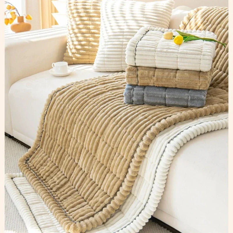 A beige corduroy sofa armrest cover draped over a white sofa, featuring stacked rectangular cushions.