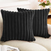 Black faux rabbit fur cushion cover pillows resting on a light-colored sofa.