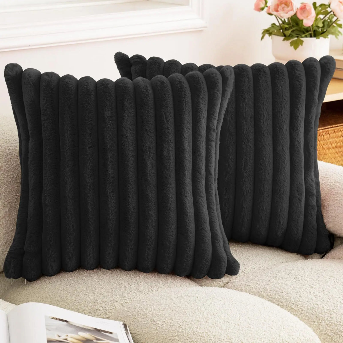 Black square faux rabbit fur cushion cover resting on a light-colored sofa.