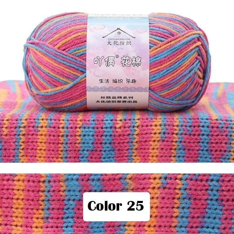 A skein of multi-colored yarn featuring pink, blue, and yellow stripes displayed on a textured pink knit background.