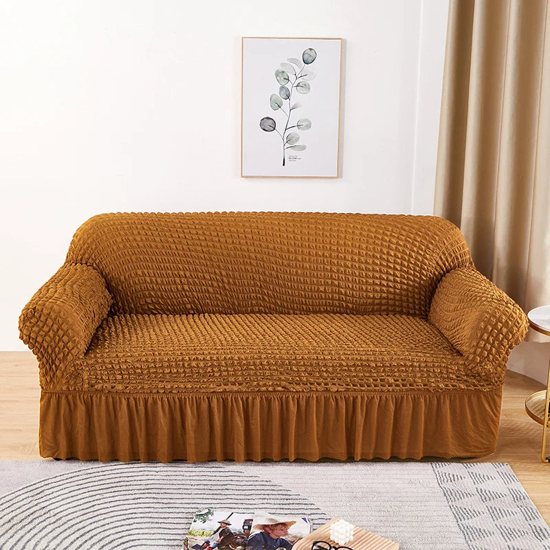 A mustard brown stretch knit sofa cover featuring a bubble lattice texture placed on a light gray rug.