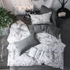 A set of three white and gray marble patterned duvet covers and pillow cases displayed on a bed.