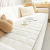A white sofa armrest cover with vertical ribbed texture and cream accent pillows on a light-colored sofa.