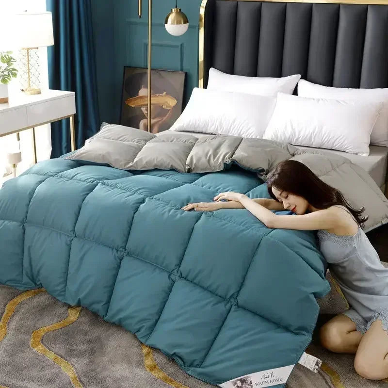A woman is relaxing on a teal quilted comforter in a bedroom setting with dark blue curtains and a black headboard.
