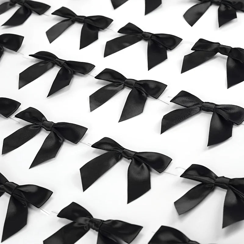 A close-up view of a black satin ribbon twist tie bow in a row against a white background.