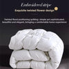A white, fluffy quilt or duvet is shown, featuring an embroidered stripe and twisted flower design.