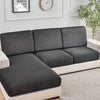 A modern gray sofa with slipcovers sits on a light rug in a bright room.