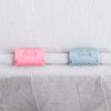 Two plastic invisible sheet clips, one pink and one light blue, are shown against a white fabric background.