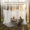 A family is eating outdoors under a spacious 3x3m sanctuary mosquito net in a forest setting.