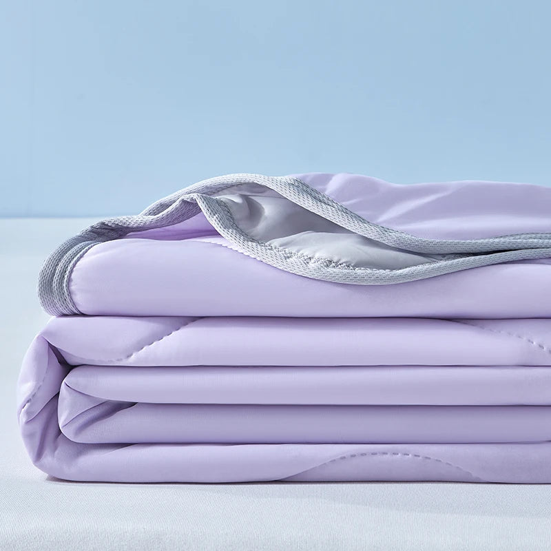 A stack of light purple cooling fiber blankets folded neatly on a white surface.