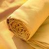 A rolled set of light yellow organic cotton bedding, showing the fabric texture and folds.