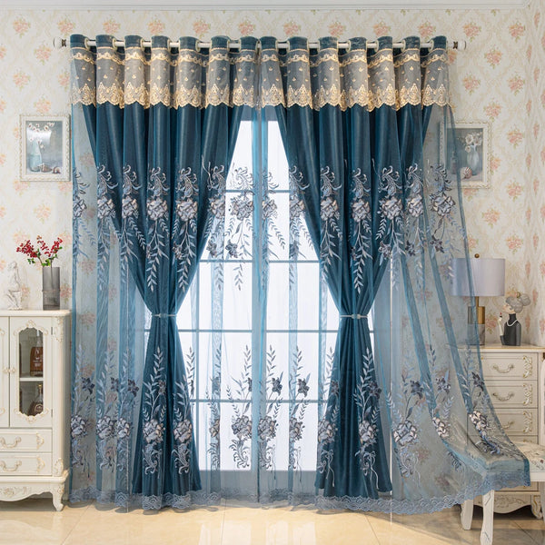 A pair of blue sheer dual-layer curtains with embroidered floral patterns hanging in a window.