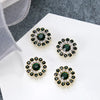 Four clusters of dark green and clear rhinestones on a white surface.