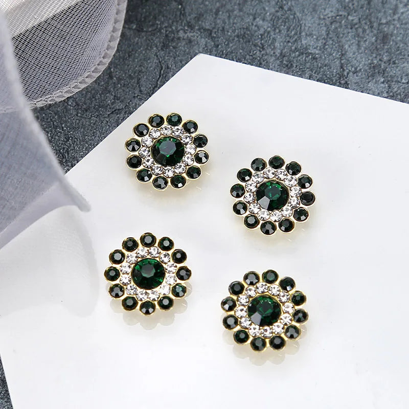 Four clusters of dark green and clear rhinestones on a white surface.
