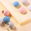 A collection of six colorful, round non-slip duvet cover clips in shades of blue, pink, and purple are displayed on a yellow 