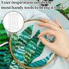 A hand holds a green fabric featuring tropical leaf patterns, with a precision sewing kit visible nearby.