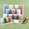A collection of colorful erasable fabric chalk markers in various shades of blue, pink, and white are displayed on a green su