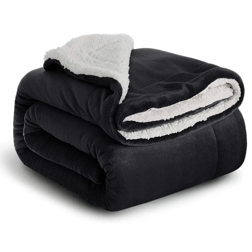 A black sherpa fleece blanket with white trim is folded and displayed.