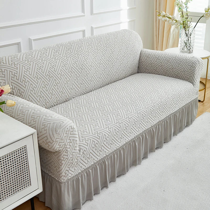 A light gray jacquard stretch sofa cover featuring a geometric woven pattern on a modern sofa.