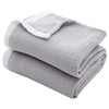 Gray muslin throw blanket folded and rolled with white trim