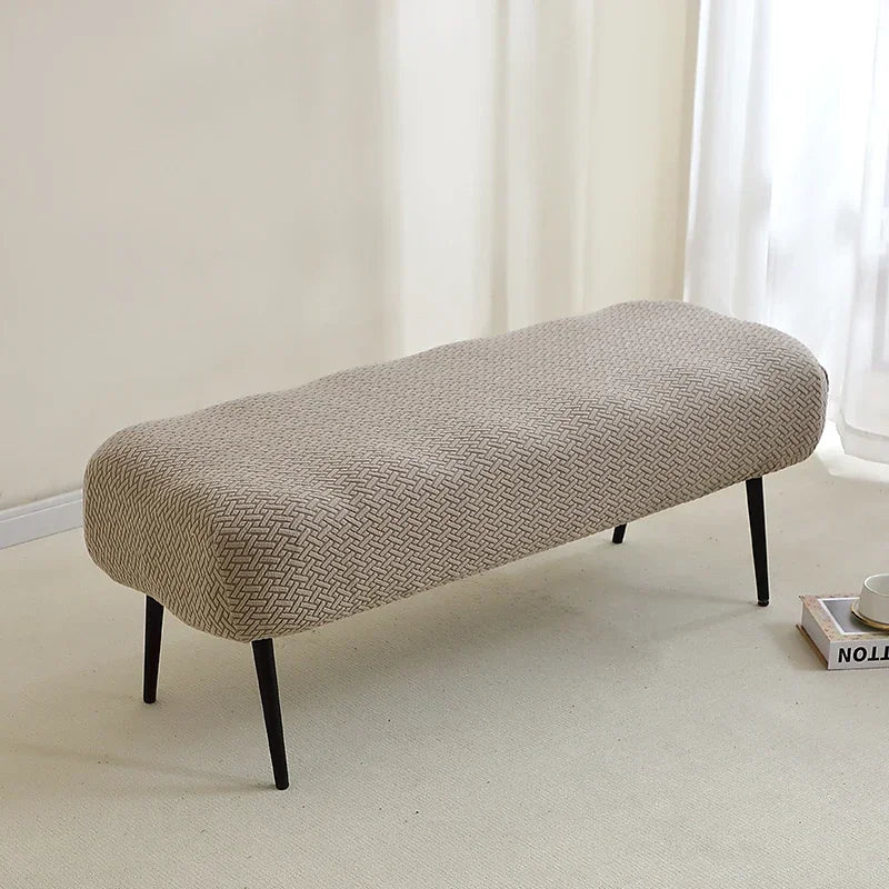 A beige elastic jacquard bench cover used as protection for a piano, dining, or entryway seat.