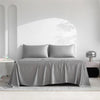 A luxury organic bamboo bed sheet set draped on a bed in a bright, minimalist room.