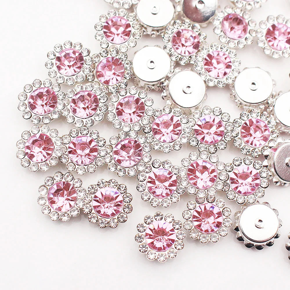 A close-up of silver and pink crystal rhinestone sew-on buttons arranged in a floral pattern.