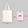 A white canvas tote bag with handles shown next to an A4 sized piece of paper for scale.