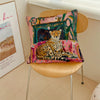 A cushion cover featuring a painting of a leopard and lush green plants on a pink background.