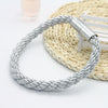 Silver braided magnetic curtain tieback clips resting on a woven mat.