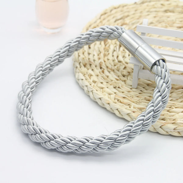 Silver braided magnetic curtain tieback clips resting on a woven mat.