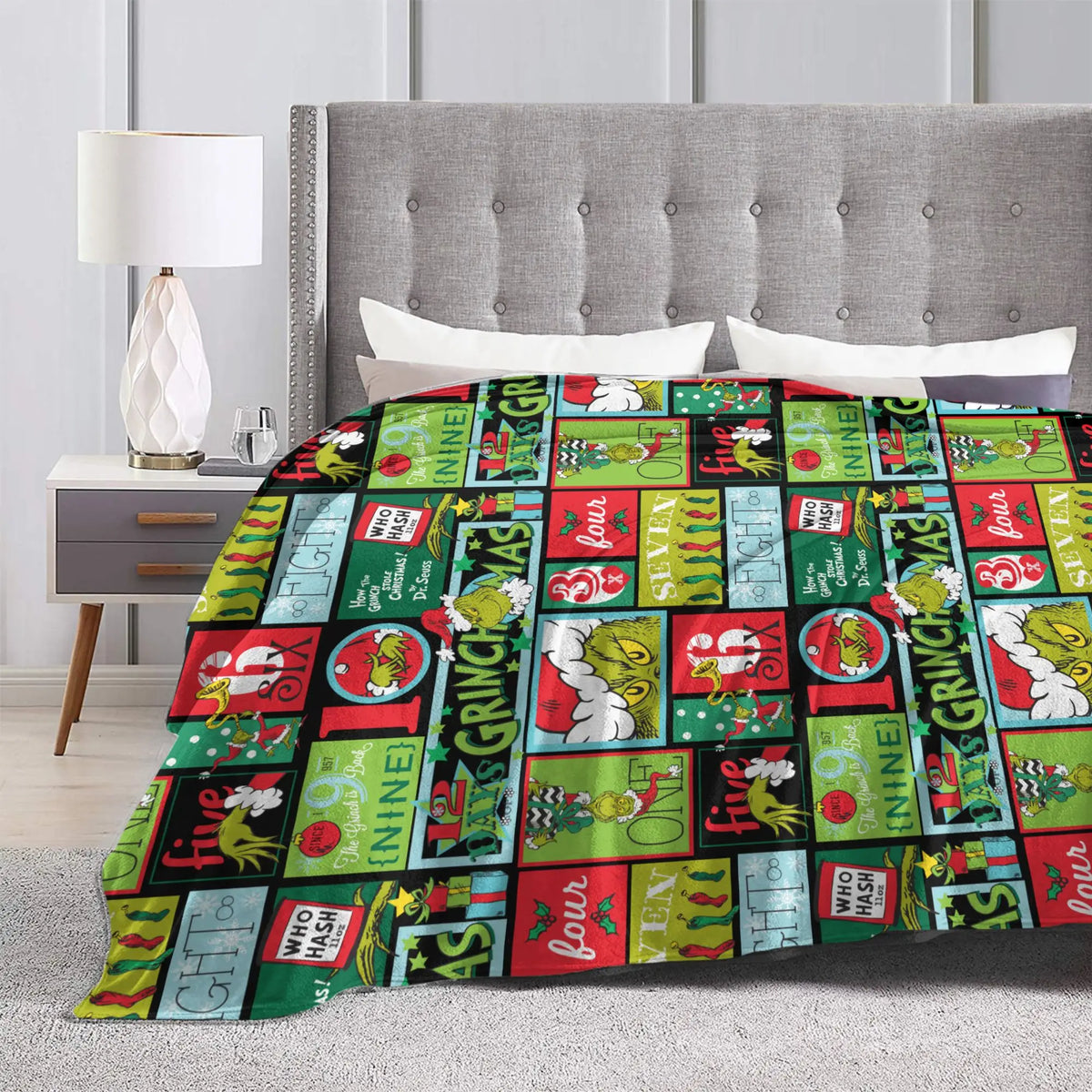 A colorful patterned throw blanket displayed on a bed with a gray upholstered headboard and white bedding.