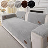 A minimalist anti-slip sofa cushion in light gray fabric with striped texture and white trim.