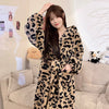 A woman models a long, leopard print flannel kimono robe in brown and black tones indoors.