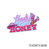 Pink and orange embroidered letter patches spelling out Howdy Honey