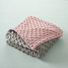 A stack of three soft fleece throw blankets in shades of pink, gray, and muted green.