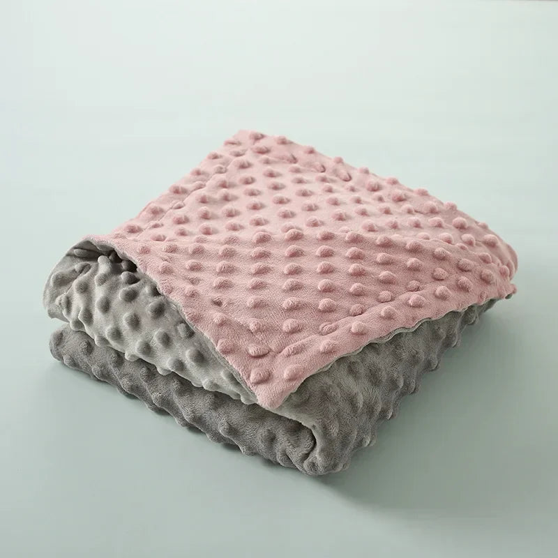 A stack of three soft fleece throw blankets in shades of pink, gray, and muted green.