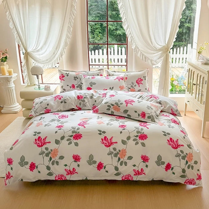 A white duvet cover set with a pink and green floral marble print displayed on a bed in a bright room.