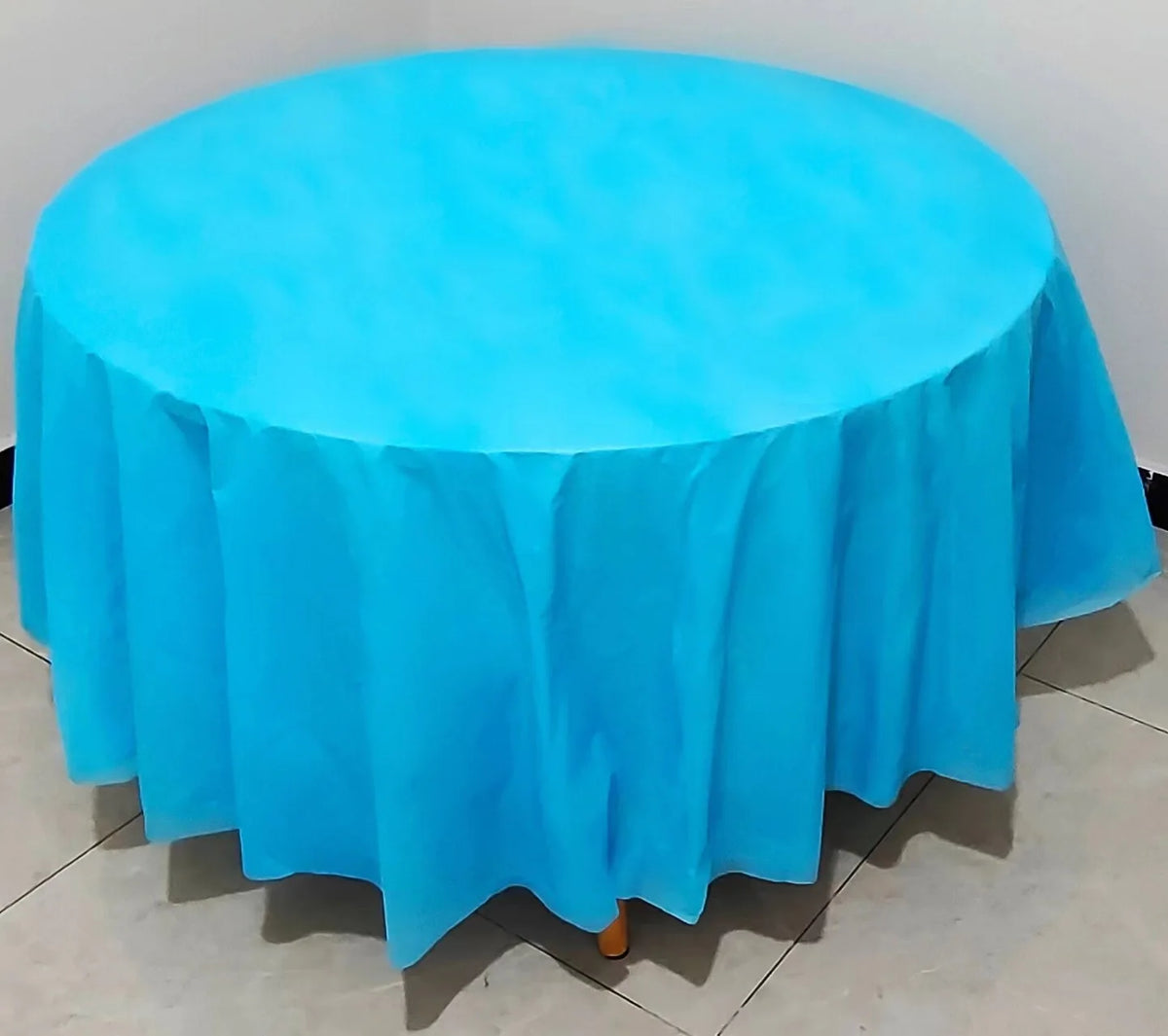 A bright blue round plastic disposable table cover spread on a white surface.