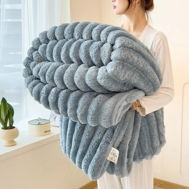 A woman holds a thick, fluffy blue and gray striped flannel blanket against her chest.