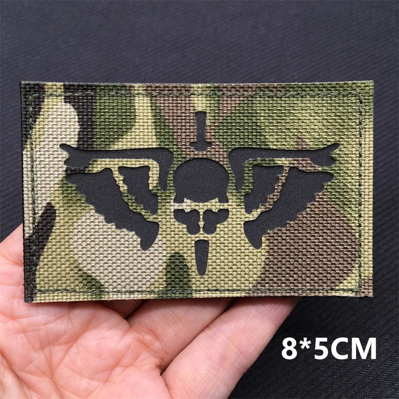 A rectangular tactical patch featuring a camouflage pattern with a silhouette of an eagle on a dark background.